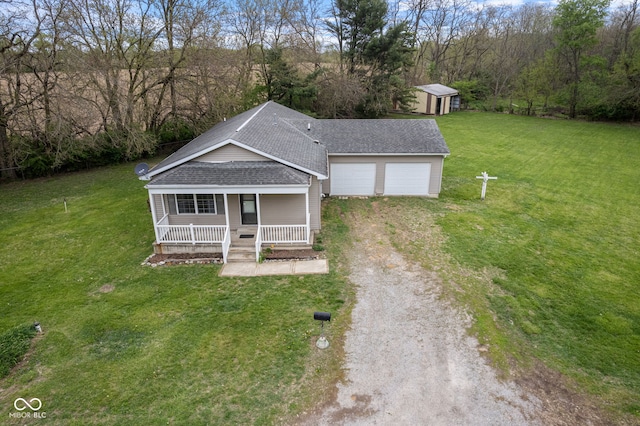 view of front facade featuring a porch, driveway, roof with shingles, a front yard, and a shed