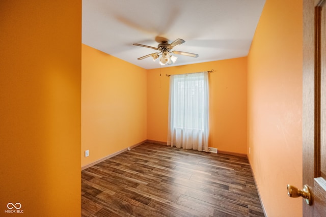 spare room featuring ceiling fan, dark wood finished floors, and baseboards