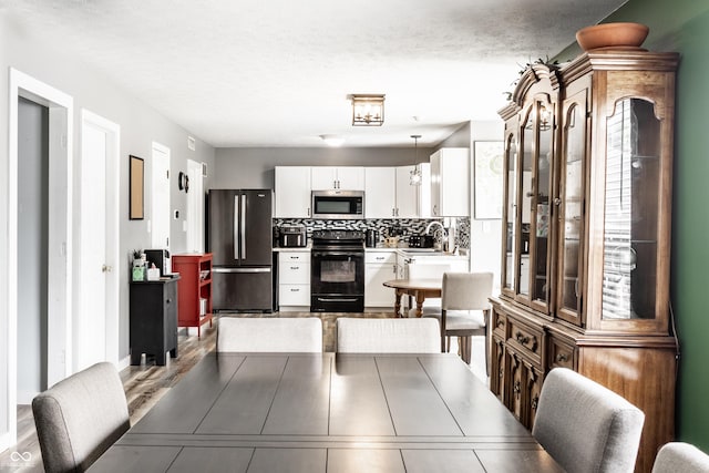 kitchen featuring electric range, freestanding refrigerator, stainless steel microwave, white cabinets, and tasteful backsplash