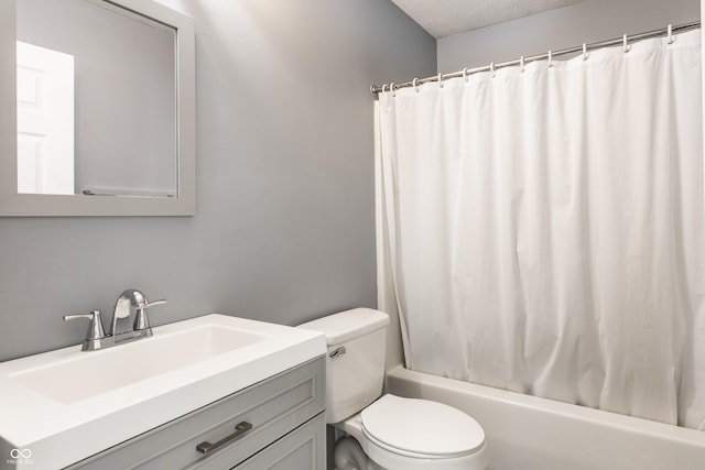 bathroom with shower / tub combo with curtain, vanity, toilet, and a textured ceiling