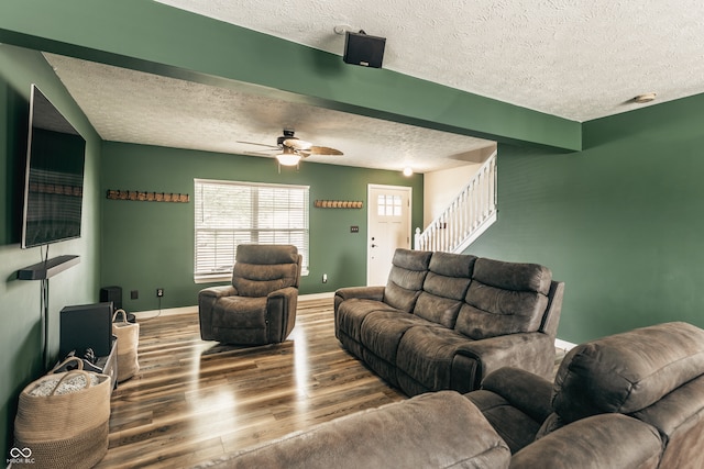 living area with a textured ceiling, wood finished floors, stairs, ceiling fan, and baseboards