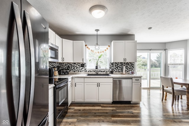 kitchen with stainless steel appliances, a sink, tasteful backsplash, dark wood-type flooring, and a textured ceiling