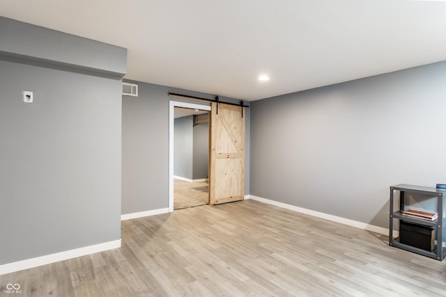 below grade area featuring a barn door, light wood finished floors, baseboards, and recessed lighting