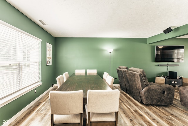 dining area featuring wood finished floors, a textured ceiling, and baseboards