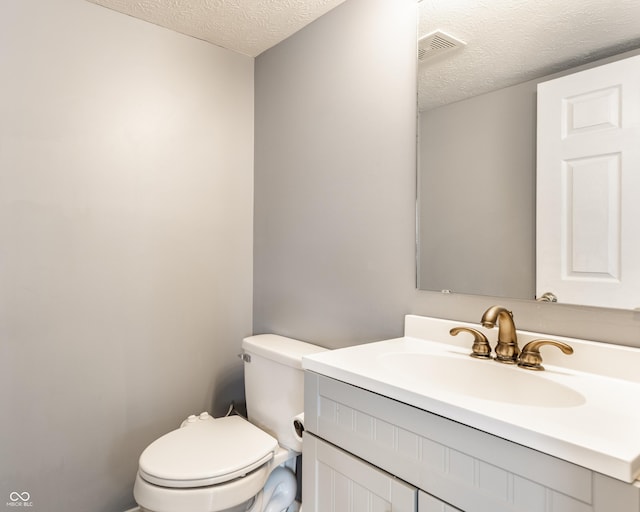 bathroom with a textured ceiling, toilet, and vanity