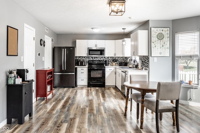 kitchen featuring stainless steel appliances, light wood finished floors, decorative backsplash, and white cabinets