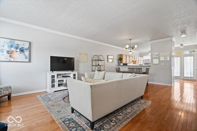 2405 N Park Ave, Indianapolis, IN 46205 - living room with light wood-style floors, a textured ceiling, crown molding, baseboards, and a chandelier