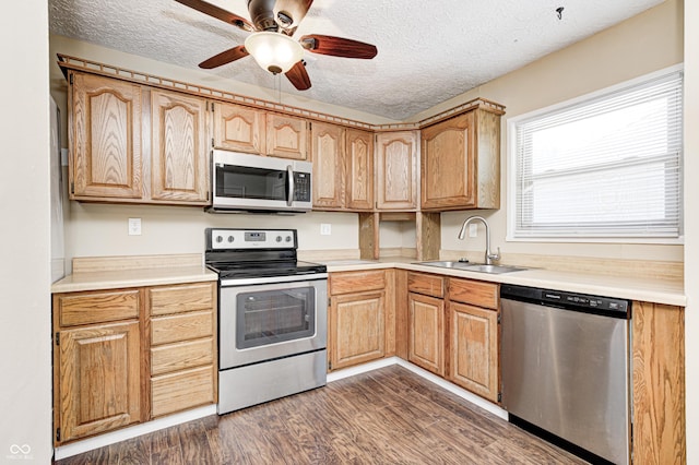 kitchen with stainless steel appliances, a sink, dark wood-type flooring, a textured ceiling, and light countertops
