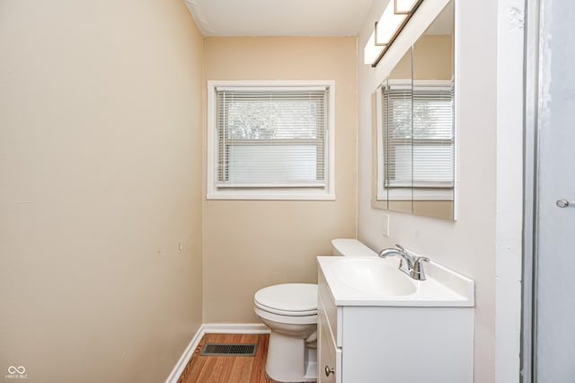 bathroom featuring toilet, wood finished floors, vanity, and plenty of natural light