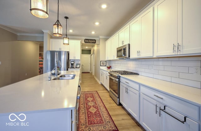 kitchen featuring stainless steel appliances, a sink, crown molding, backsplash, and light countertops
