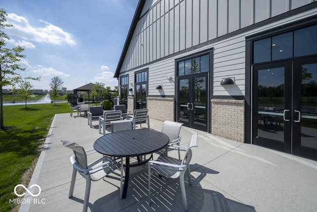 view of patio / terrace featuring french doors, a water view, and outdoor dining area