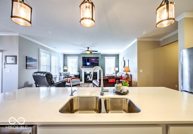 kitchen with a sink, a glass covered fireplace, open floor plan, ceiling fan, and crown molding