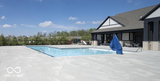 community pool with a patio area and fence