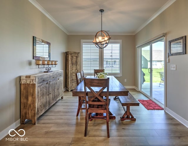 dining area with a chandelier, ornamental molding, light wood-style floors, and baseboards