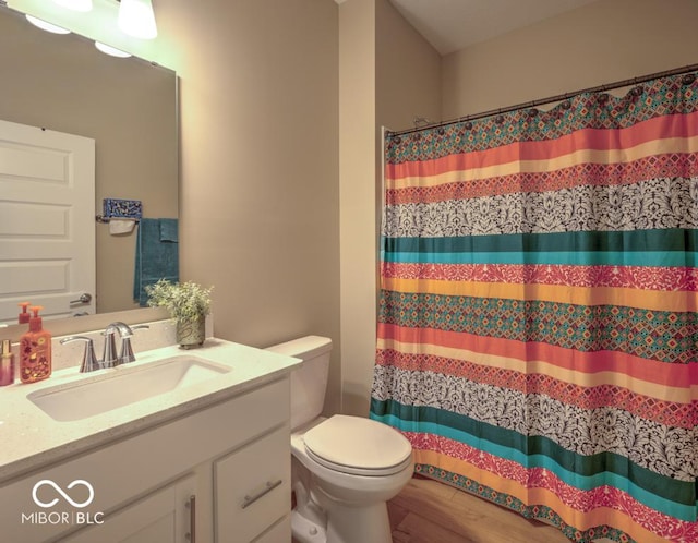 bathroom with toilet, vanity, a shower with shower curtain, and wood finished floors