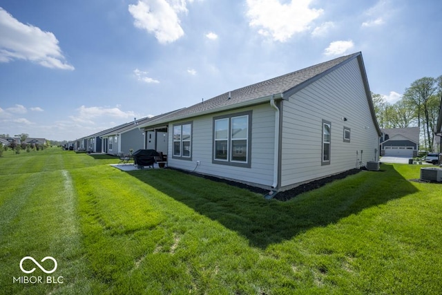 rear view of property with cooling unit, a lawn, and a shingled roof
