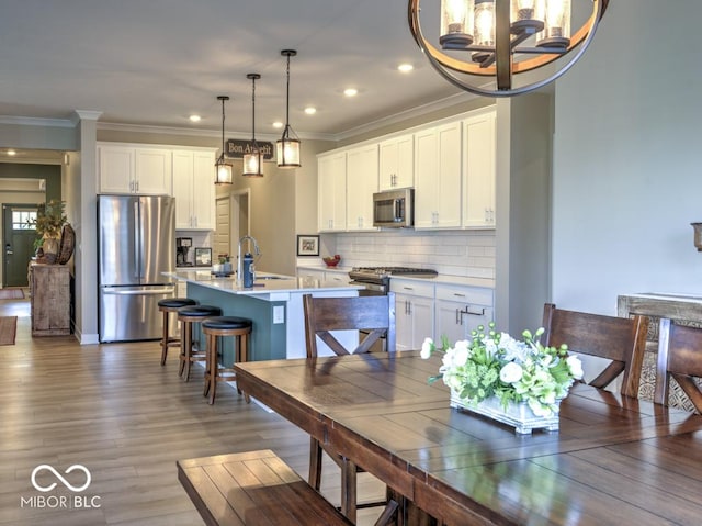 dining room with wood finished floors, ornamental molding, a chandelier, and recessed lighting
