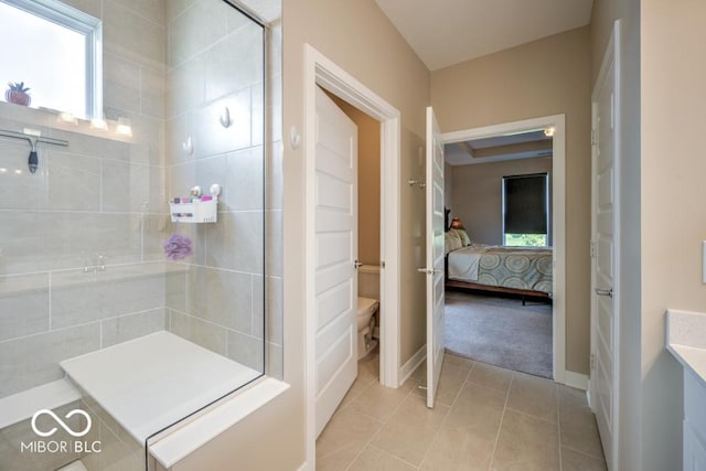 full bath with a tile shower, toilet, tile patterned flooring, connected bathroom, and baseboards