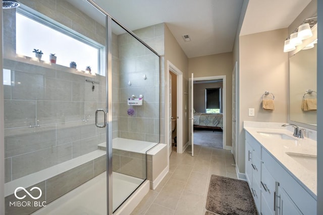 ensuite bathroom featuring a shower stall, tile patterned flooring, baseboards, and double vanity