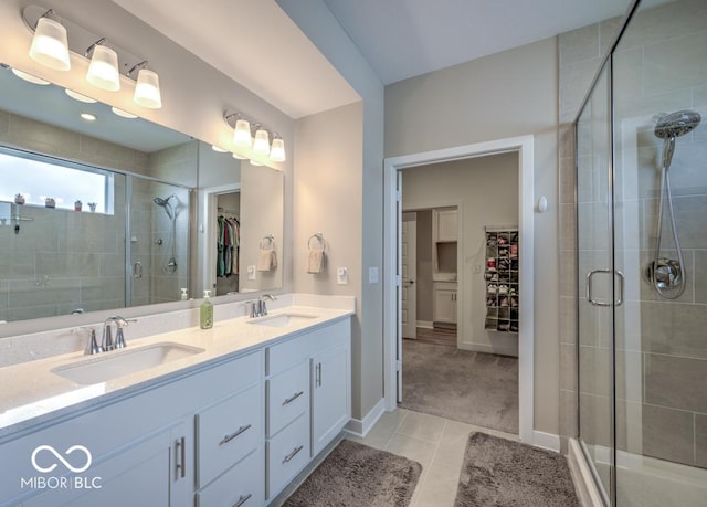 bathroom with a stall shower, tile patterned flooring, double vanity, a walk in closet, and baseboards