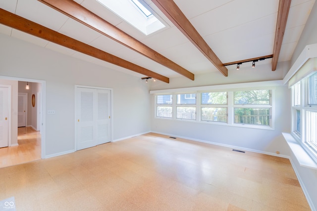 unfurnished living room with light floors, baseboards, beamed ceiling, and a skylight