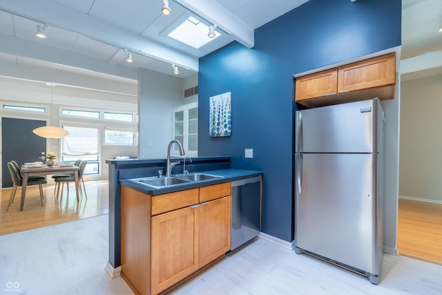 kitchen featuring appliances with stainless steel finishes, rail lighting, a sink, and light wood-style floors