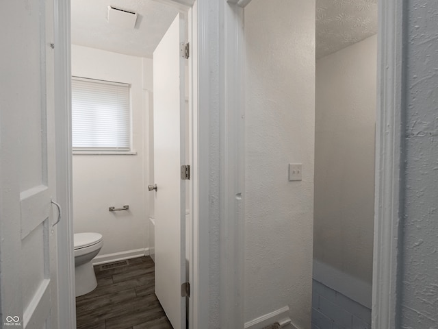 bathroom with wood finished floors, toilet, and baseboards