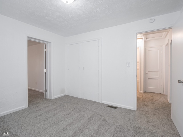 unfurnished bedroom featuring carpet floors, a closet, baseboards, and a textured ceiling