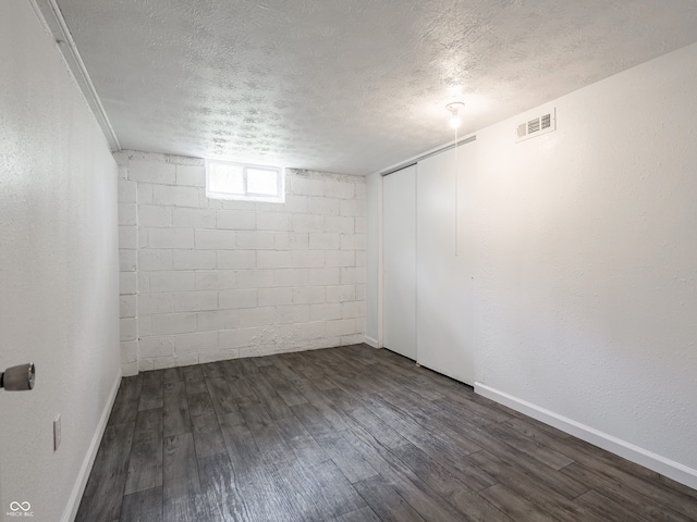 below grade area with dark wood finished floors, a textured ceiling, and baseboards