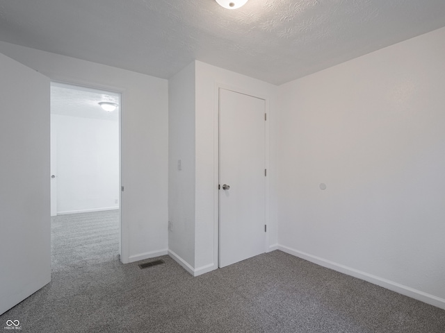 carpeted empty room featuring baseboards and a textured ceiling