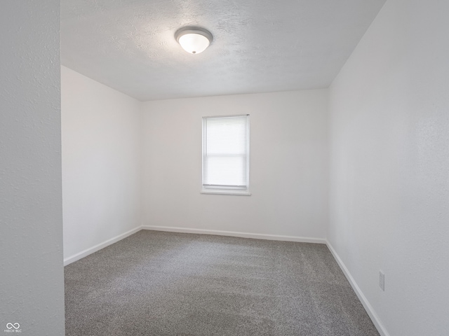 carpeted spare room with baseboards and a textured ceiling