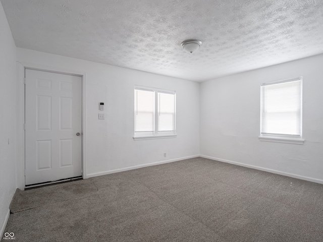 empty room featuring baseboards, a textured ceiling, and carpet floors