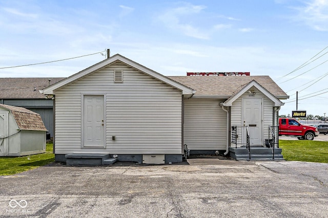 1391 N Shadeland Ave, Indianapolis, IN 46219 - view of front of home with a shed, entry steps, a shingled roof, and an outdoor structure