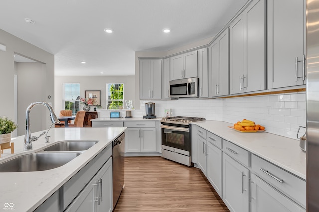 3546 Brampton Ln, Westfield, IN 46074 - kitchen featuring stainless steel appliances, a sink, gray cabinets, light wood finished floors, and backsplash