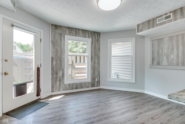 unfurnished dining area with wood finished floors, baseboards, and a textured ceiling