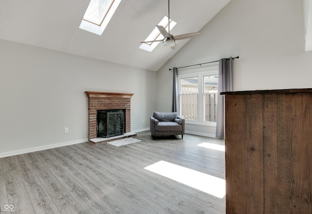 living room featuring high vaulted ceiling, wood finished floors, a fireplace, a skylight, and baseboards