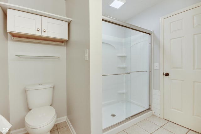bathroom featuring a stall shower, tile patterned floors, toilet, and baseboards