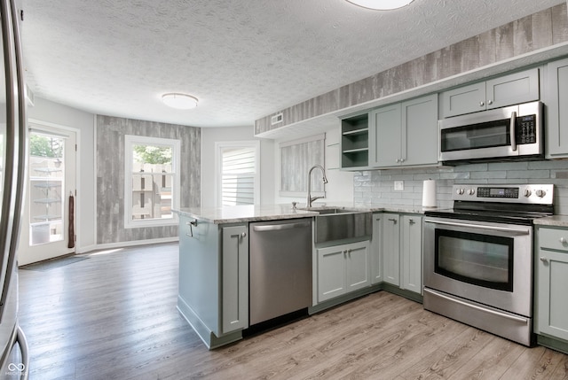 kitchen with stainless steel appliances, gray cabinetry, a peninsula, and a textured ceiling