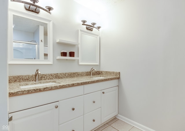 full bath with tile patterned floors, double vanity, an enclosed shower, and baseboards