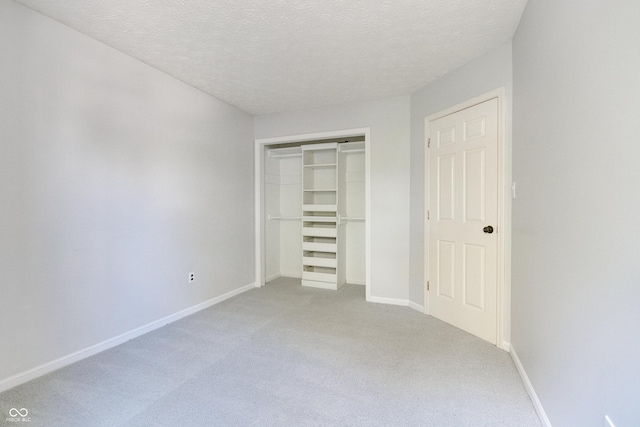unfurnished bedroom with carpet floors, a closet, baseboards, and a textured ceiling