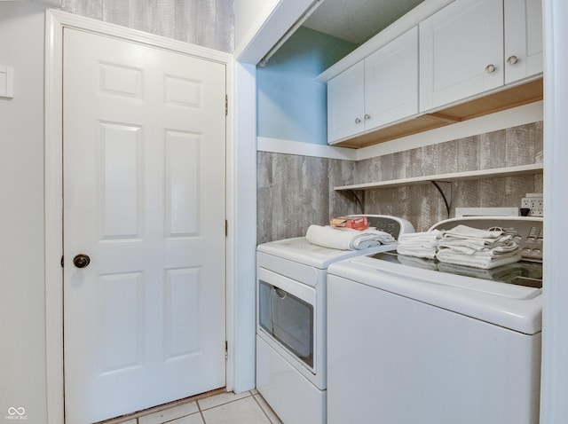 laundry area with washing machine and clothes dryer, cabinet space, and light tile patterned floors