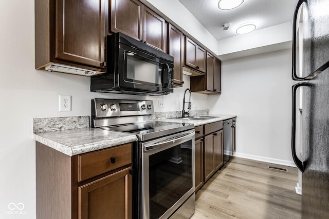 1142 Canterbury Sq S Unit B, Indianapolis, IN 46260 - kitchen featuring black appliances, a sink, light wood-style flooring, light countertops, and dark brown cabinets