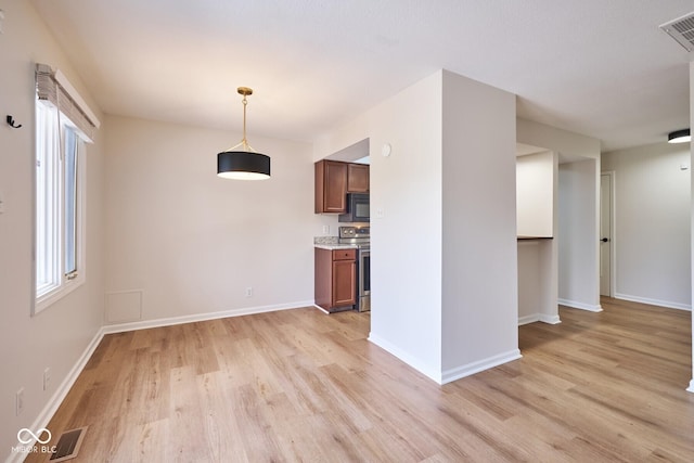 1142 Canterbury Sq S Unit B, Indianapolis, IN 46260 - kitchen with black microwave, stainless steel range with electric cooktop, light wood-type flooring, and brown cabinets