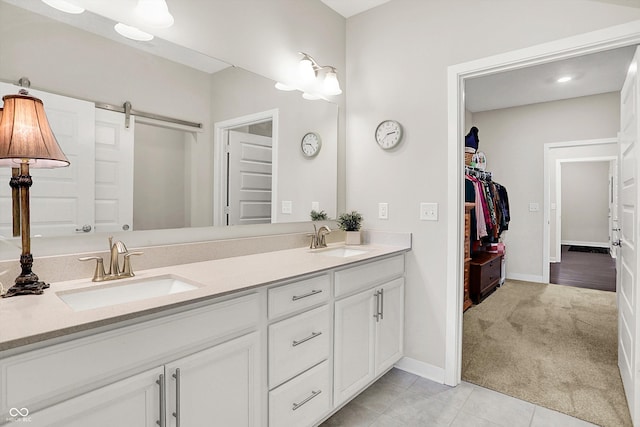 full bathroom with a spacious closet, double vanity, baseboards, and tile patterned floors