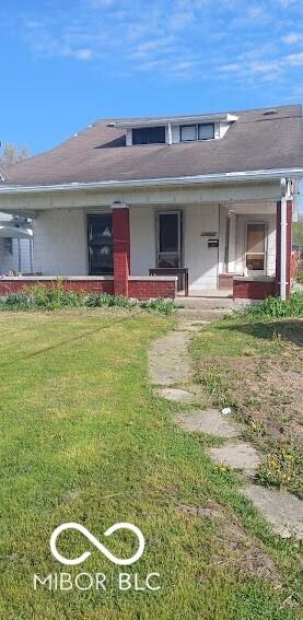 view of front of property featuring a front lawn, covered porch, and brick siding