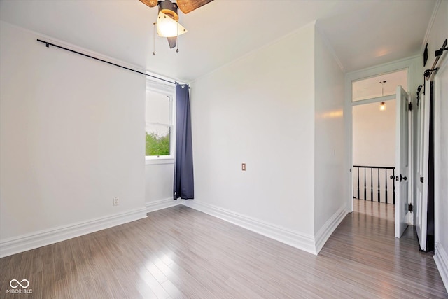 spare room featuring ceiling fan, wood finished floors, baseboards, and crown molding