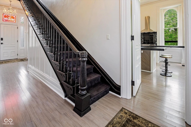 stairs with a chandelier, wood finished floors, and baseboards