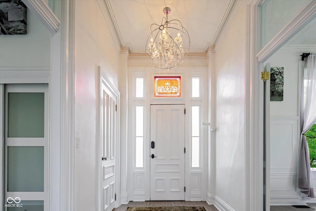 foyer with a chandelier, ornamental molding, healthy amount of natural light, and baseboards