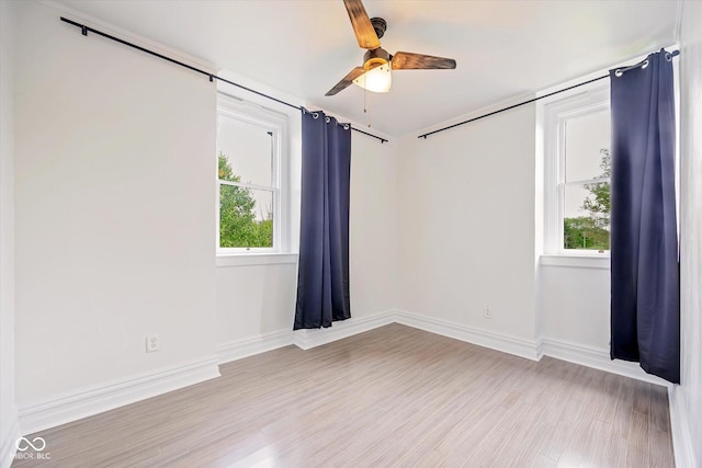empty room featuring ceiling fan, light wood-style flooring, and baseboards