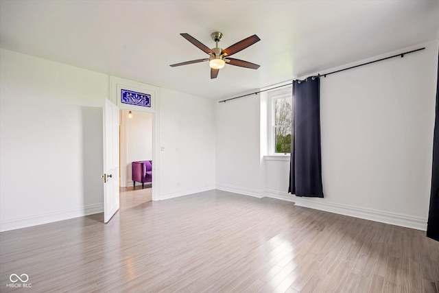 spare room featuring a ceiling fan, wood finished floors, and baseboards